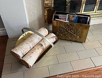 Photo showing the wooden log holder with brass finish handle holding birch logs beside the matching brass finish wooden magazine rack containing magazines.