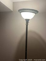 Close-up of the frosted glass shade and brushed nickel base of the floor lamp, showing the top portion and some detailing on the shade.