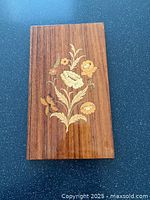 Front view of the rectangular wooden plaque showing detailed floral marquetry inlay with flowers and leaves in various wood tones on a medium brown background.