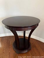 Front angle showing the round tabletop, carved legs, and circular base.