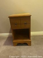 Full front view of side table showing drawer and open storage area with decorative base.