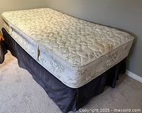 Twin mattress and box spring set on metal bed frame, showing entire bed setup and mattress surface