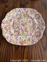 Top view of James Kent Fenton DuBarry chintz china scalloped plate with pink, yellow, and white flowers pattern on wooden surface.