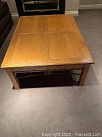 Top angled view of solid wood coffee table showing paneled top and metal side decoration