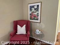 Side-angle view of the cranberry wing chair with a white pillow, showing details and surroundings.