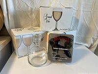 18 Everyday Wine Glasses by Luminarc in boxes, glass carafe with stopper, and Houdini lever corkscrew in package.