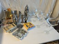 Front shot showing all items including martini glasses, shakers, jiggers, ice bucket, picks, strainer, spoon, muddler and napkins.