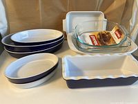 Photo showing assortment of ceramic and glass baking and serving dishes, including Emile Henri, Chantal, Le Creuset, and Pyrex items stacked and arranged together