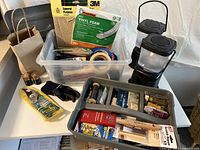 Photo of tools and supplies in plastic containers including vinyl foam, adhesive tapes, gloves, batteries, brass fasteners, and battery operated lanterns