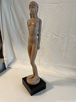 Front view of nude female sculpture on black base.