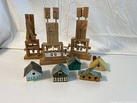 All nine items from the front, showing the four wooden figurines in the back and five small painted wooden birdhouses in front.