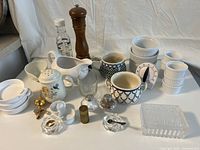 Overview of assorted cream and sugar serving pieces along with kitchen items on white surface showing variety and condition.