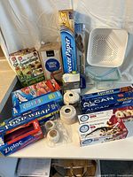 Photo showing various kitchen storage wraps, bags, twine, and a white plastic colander arranged on a table.