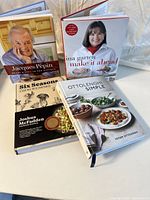 Photo showing five cookbooks stacked and standing partly spread out: Jacques Pépin cookbook with his portrait, Ina Garten's "Make It Ahead", Yotam Ottolenghi's "Simple", Joshua McFadden's cookbook, and "Six Seasons" about cooking with vegetables.