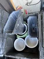 Photo of plastic and ceramic planters inside a large plastic tote including two rectangular planters, round white planters, and a green ceramic planter.