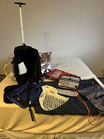 Full view of the black wheeled duffel bag along with the cosmetic bags, packing cubes, and net bag arranged on a bed