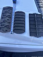 All three cast iron muffin pans placed side by side on a white surface with tape measure showing sizes.