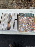 Storage box with multiple stacks of Yu-Gi-Oh cards and loose cards on table