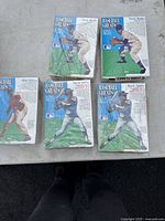 Five Kellogg's Cornflakes cereal boxes laid out on a flat surface showing front with baseball player images and one with visible cutout outline.