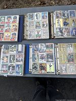 Six binders opened and displayed, showing multiple pages of baseball cards inside plastic sleeves, various players and card designs visible.