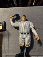 Photo of the 12-inch plastic Babe Ruth doll in pinstriped attire holding a cap.