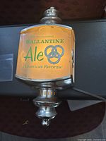 Front view of Ballantine Ale light showing amber translucent panel with green logo and text, with silver metal frame.