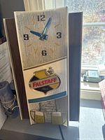 Full view of the Falstaff Beer wall clock showing clock face, lighted logo, and bubble effect on clock face