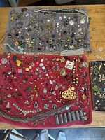 Full overview of mostly mismatched earrings, necklaces, bracelets, brooches laid out on cloths.