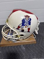 Side view of white football helmet phone showing classic Pat Patriot logo and coiled handset cord