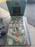 Full view of the vintage tabletop pinball machine showing horse racing theme and condition of playing field, clear plastic cover, and back scoreboard panel with Sweepstakes branding.