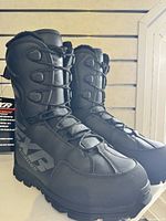 Front and side view of pair of boots against a slatwall background