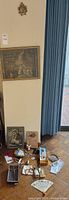 Full lot overview of all items arranged on floor and leaning against wall under a framed artwork and a small gold-toned religious icon above