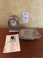 The full set showing the silver plated pedestal tray, Stoney Creek Trading Company clock, and accompanying paper.