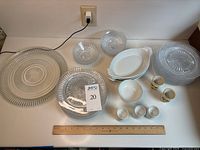 Full display of all glass plates, dessert plates, ice cream bowls, ceramic baking dishes, assorted egg cups, and pedestal bowl on table.