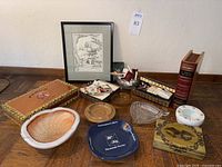 Lot overview showing cigar boxes, ashtrays, matchbooks, and framed drawing on wooden surface