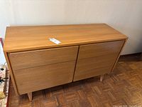 Front perspective showing overall shape, slatted drawer fronts and light wood finish