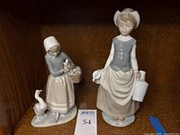Front view of the Milkmaid and Goose Girl Lladro figurines displayed on shelf with lot number 54