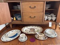 China displayed inside a wooden credenza with turkey platter, gravy boat, and quail and pear salt and pepper shakers in front