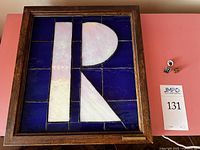 Framed stained glass logo and three pins arranged on table