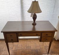 Overall view of wooden desk with lamp on top