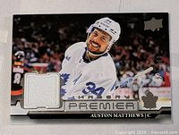 Front photo of 2022-23 Upper Deck Premier Auston Matthews game-worn jersey card with player image, jersey swatch, and serial number 20 of 100.