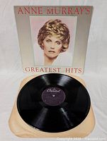 Vinyl LP record on paper sleeve with visible label, reflecting light in black shiny surface