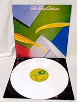 Front of the LP cover with the white vinyl record positioned in front, showing colorful geometric abstract artwork on cover.