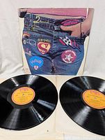 Two black vinyl records with yellow and pink PIK labels showing sides A and B for the compilation.