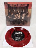 Photo showing red vinyl 45 RPM record and front of sleeve with band photo and title.