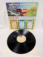 Front cover of The Guess Who 'Artificial Paradise' vinyl LP record showing colorful cartoon artwork with fork in road theme and game instructions.