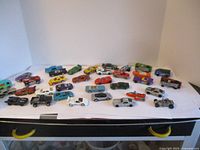 Wide view of the 34 Hot Wheels cars arranged on a white surface showing a variety of models and colors.