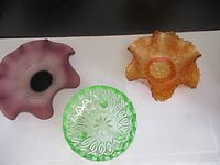Top-down view of the three bowls showing purple swirl, amber carnival glass, and green leaf pattern bowls