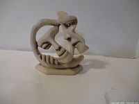 Front view of abstract ceramic art sculpture showing intertwined faces and smooth beige surface.
