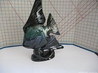 Angled view of the blue and black glazed ceramic angel fish statue showing detailed fins and textured scales with a curved base.